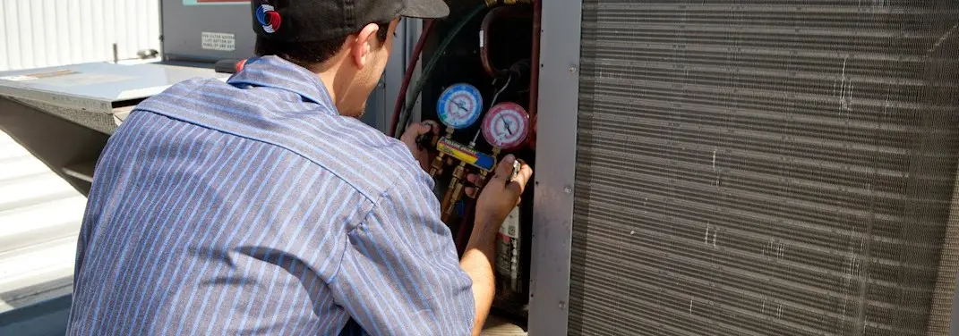 HVAC technician servicing a condenser unit in Guadalupe