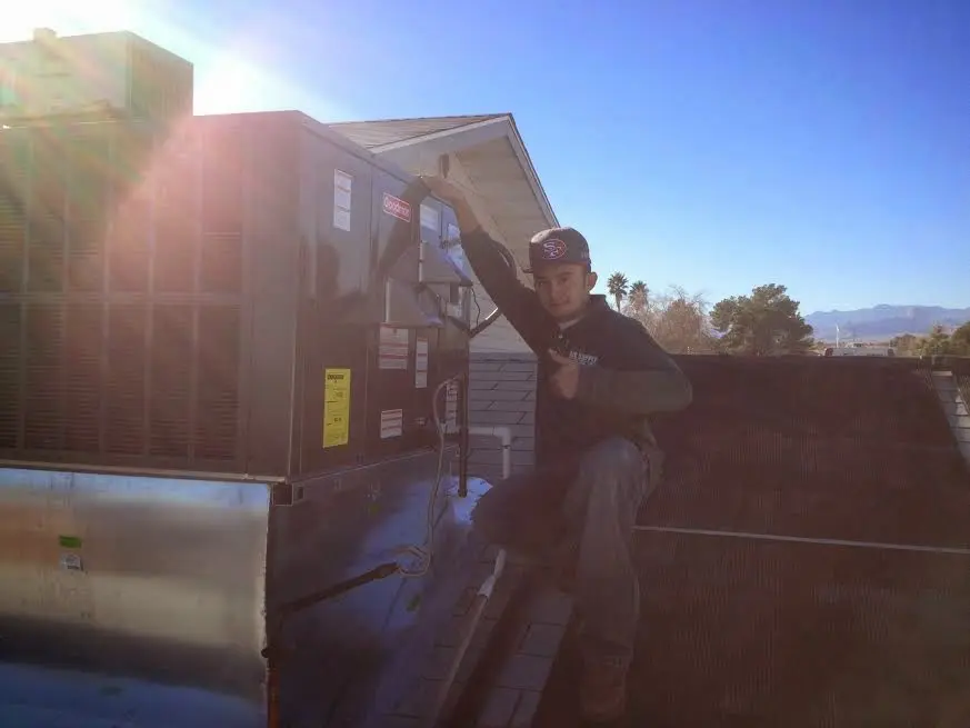 HVAC technician performing Air Duct Repair on a rooftop unit in Guadalupe